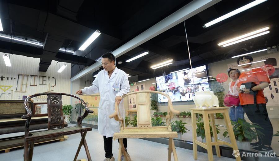 游客在陕西历史博物馆观看展厅文物修复室内修复师的工作。
